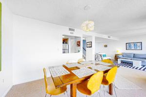 une salle à manger avec une table en bois et des chaises jaunes dans l'établissement Captains Court 1031, à Fernandina Beach