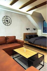 ein Wohnzimmer mit einem Sofa, einem Bett und einer Uhr in der Unterkunft Blackwood Hill in Belgrad