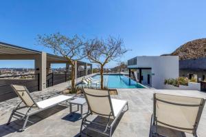a patio with two chairs and a swimming pool at Lumina at Cardinal Cabo San Lucas in Cabo San Lucas