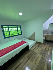 a bedroom with two beds and a large window at Apartamentos La Gloria Guatapé in Guatapé