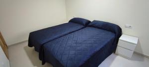 ペニスコラにあるApartamentos Peñiscola Argualasの白い壁のドミトリールームの青いベッド1台分です。