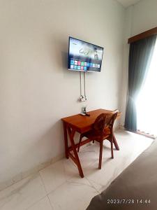 a wooden desk with a television on a wall at Loka Anyar Guest House in Kerobokan
