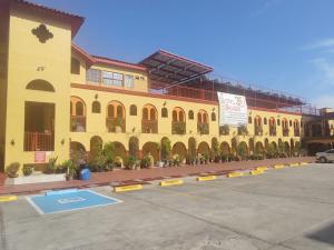 a yellow building with potted plants in a parking lot at HOTEL SEVILLA in Tijuana