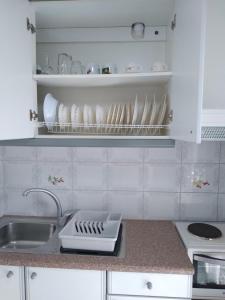a kitchen with a sink and a counter with dishes on shelves at Makis Studios & Apartments in Poros