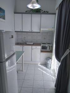  La cuisine est équipée de placards blancs et d'un réfrigérateur. dans l'établissement Makis Studios & Apartments, à Poros