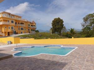 a swimming pool in front of a yellow building at Round View Guest House in Port Antonio