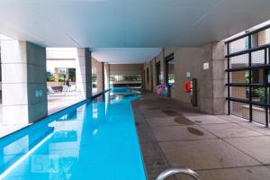 a large swimming pool with blue water in a building at Flat em Moema (SP) in Sao Paulo