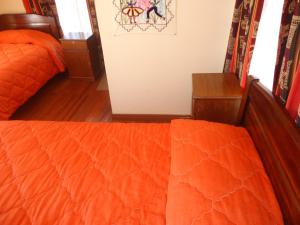 a bedroom with an orange comforter on a bed at Hostal del Sol Isla del Sol in Isla de Sol
