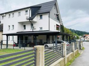 a white house with a fence in front of it at Apartments with parking space Delnice, Gorski kotar - 21611 in Delnice