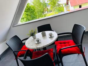 a table and chairs with red cushions and a window at Apartments with parking space Delnice, Gorski kotar - 21611 in Delnice