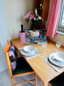 a wooden table with plates and glasses on it at Mountain View Shepherds Hut in Kilkeel