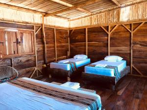 a room with three beds in a log cabin at Palaa Mayapo Ecolodge in Mayapo