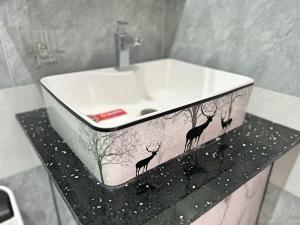 a bathroom sink with two deer painted on it at QV Luxury Apartment in Phan Rang