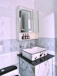 een witte badkamer met een wastafel en een spiegel bij QV Luxury Apartment in Phan Rang