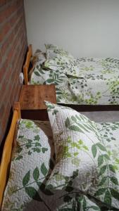 two beds with green and white pillows and a table at Cabaña Rayen in Esquel