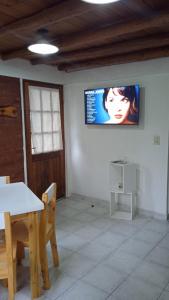 Habitación con mesa y TV en la pared. en Cabaña Rayen en Esquel