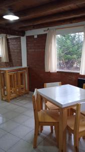 comedor con mesa, sillas y ventana en Cabaña Rayen en Esquel