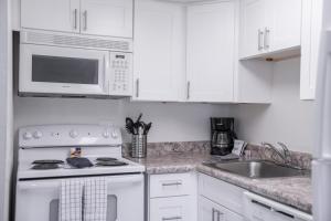 Il comprend une cuisine blanche équipée d'une cuisinière et d'un four micro-ondes. dans l'établissement 146 Fully Furnished 1BR Suite-Pet Friendly, à Scottsdale