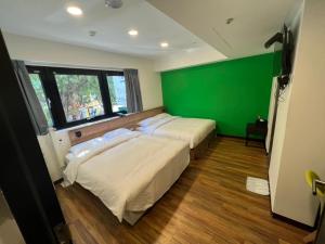 two beds in a room with a green wall at 悦心旅Yesing Hotel in Taipei