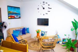 uma sala de estar com cadeiras e um relógio na parede em Relaxing Blue Flat near beach! em Calheta Do Maio