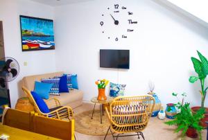 a living room with chairs and a clock on the wall at Relaxing Blue Flat near beach! in Calheta Do Maio