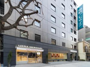 un grande edificio grigio con un negozio di fronte di Sotetsu Fresa Inn Ochanomizu Jimbocho a Tokyo