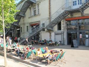 un grupo de personas sentadas en sillas de jardín frente a un edificio en Voyage à Little Havana en Bouguenais