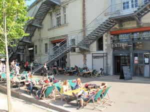 een groep mensen die in tuinstoelen voor een gebouw zitten bij Voyage à Little Havana in Bouguenais