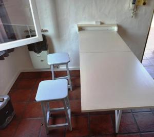 two stools sitting next to a white counter in a kitchen at Departamento 1º P, 2 personas, WIFI, confortable, mucha luz natural in Godoy Cruz