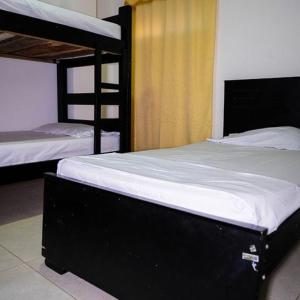a bedroom with two bunk beds with white sheets at Jiisot Hotel in Camarones