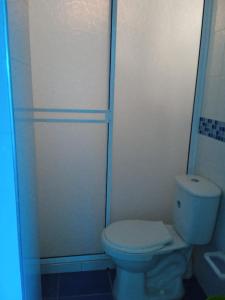 a white bathroom with a toilet and a shower at Jiisot Hotel in Camarones