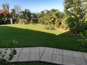 un patio de césped con una acera y un campo de hierba en Les ptits flamboyants, en Basse-Terre
