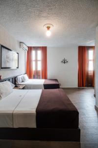 two beds in a hotel room with orange curtains at Hotel Don Quijote Plaza - Guadalajara Centro Historico in Guadalajara +90 photos