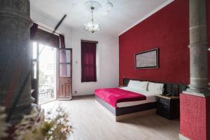 1 dormitorio con 1 cama con pared roja en Hotel Don Quijote Plaza - Guadalajara Centro Historico, en Guadalajara