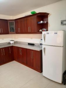 eine Küche mit einem weißen Kühlschrank und Holzschränken in der Unterkunft Andaluz Townhouse for Rent in Loja