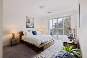 um quarto com uma cama e uma grande janela em Treetop coastal getaway in Avalon Beach em Avalon