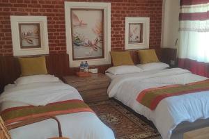 a bedroom with two beds and a brick wall at Raniban Suites - Studio Apartment in Kathmandu
