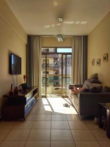 uma sala de estar com um sofá e uma televisão em Condominio Chateau Mondrian em Cabo Frio