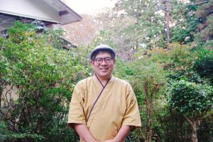 um homem de óculos e um chapéu em frente às árvores em YUPOPPO Hakone em Hakone