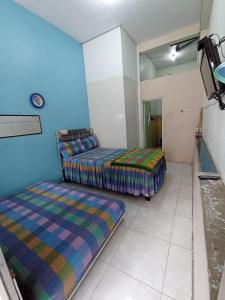 two beds in a room with blue walls at Villa Lilly in Batu