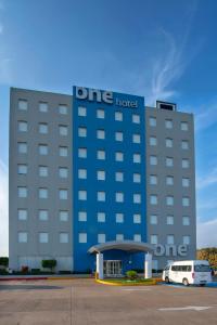 un hotel azul con una furgoneta blanca estacionada frente a él en One Coatzacoalcos Forum en Coatzacoalcos