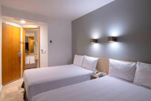 a hotel room with two beds and a mirror at One Coatzacoalcos Forum in Coatzacoalcos