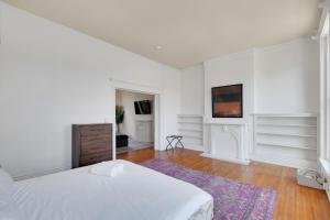 a white bedroom with a bed and a rug at Historic Guthrie Coke Lofts, Downtown Louisville in Louisville