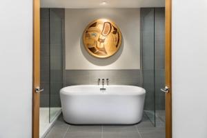 un bagno con vasca bianca e un dipinto sul muro di Kwa'lilas Hotel a Port Hardy