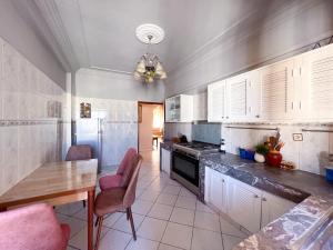 uma cozinha com armários brancos e uma mesa e cadeiras em Appartement en plein centre ville em Kenitra