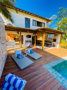 a wooden deck with blue pillows and a house at Casa Odara Trancoso in Trancoso