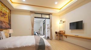 a bedroom with a bed and a flat screen tv at 逐鹿森林民宿-無電梯 in Yuchi