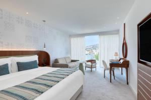リマソールにあるParklane, a Luxury Collection Resort & Spa, Limassolの大きなベッドと椅子が備わるホテルルームです。