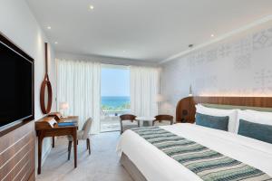 リマソールにあるParklane, a Luxury Collection Resort & Spa, Limassolの大きなベッドと大きな窓が備わるホテルルームです。