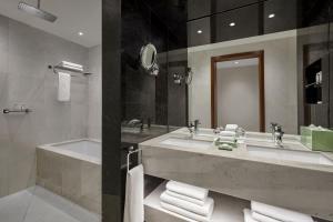 a bathroom with two sinks and a tub and a mirror at Parklane, a Luxury Collection Resort & Spa, Limassol in Limassol